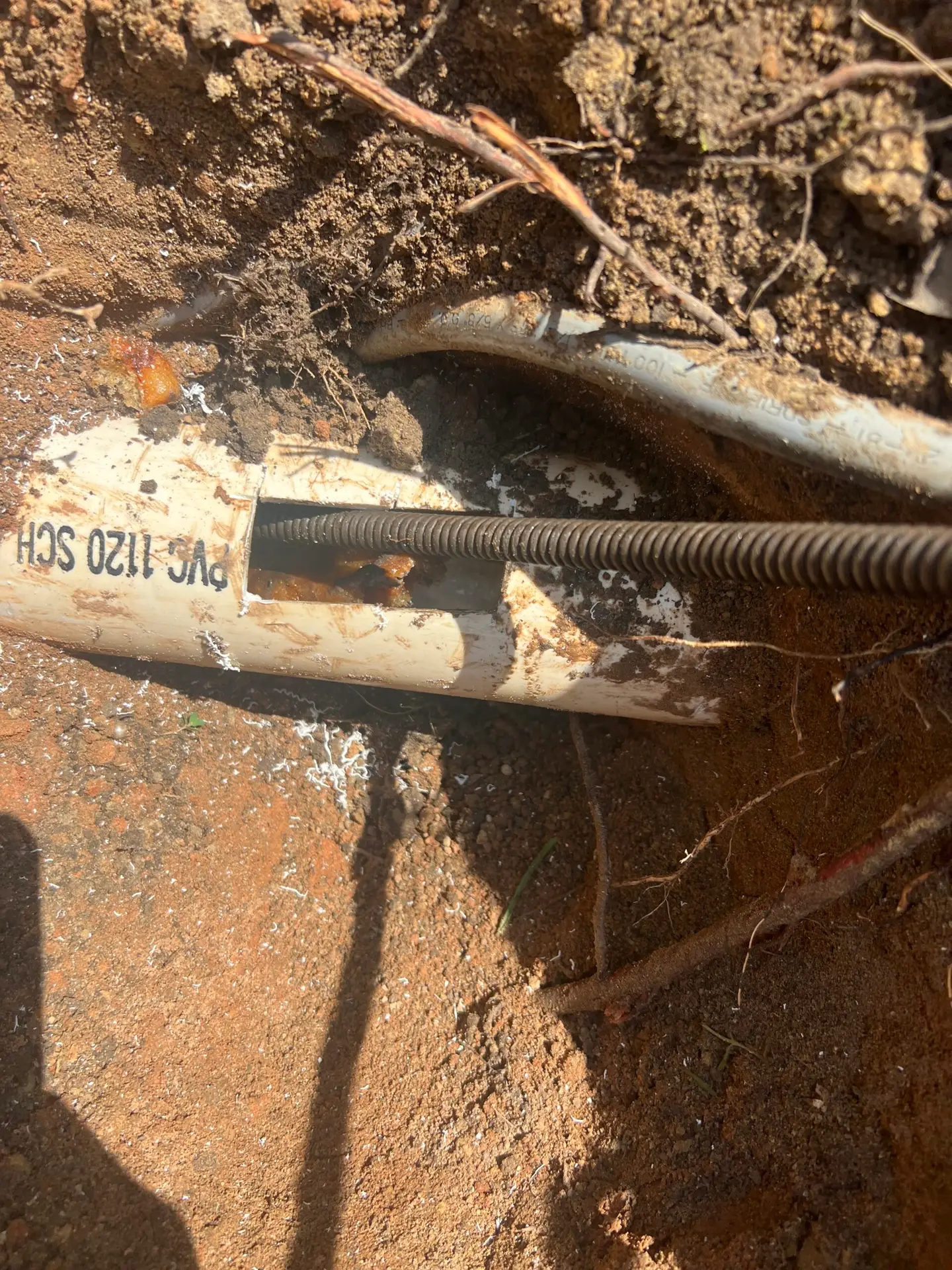 Plumber from Adams Plumbing & Drain Company clearing a clogged drain in Claremont, AL home